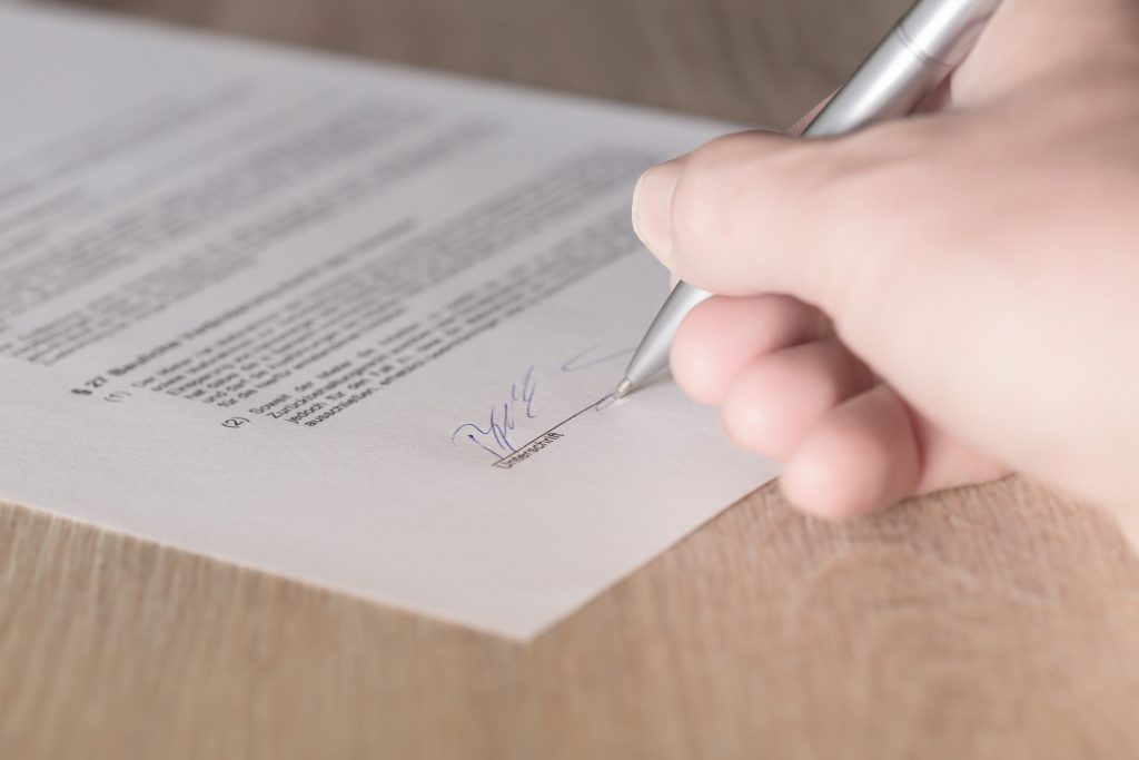 A close-up view of a hand signing a contract