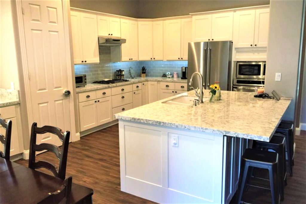 A view of a beautiful kitchen after cabinet refacing, featuring white cabinets with shaker-style doors