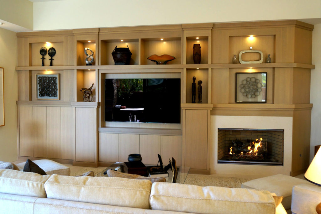 A beautiful, custom-built entertainment center with art niches and built-in lighting
