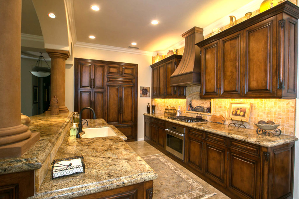 A kitchen remodel done in traditional style, with stone countertops, tile backsplash and raised panel cabinet doors