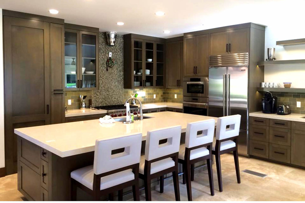 Beautiful contemporary kitchen remodel with white countertops, dark finish cabinets with shaker style doors, and a large central island